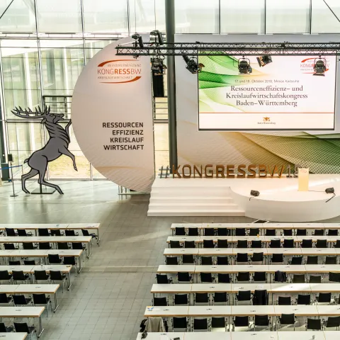 Bestuhlter Saal und Bühnenbild mit Greif und Hirsch des KONGRESS BW im Foyer der Karlsruher Messe